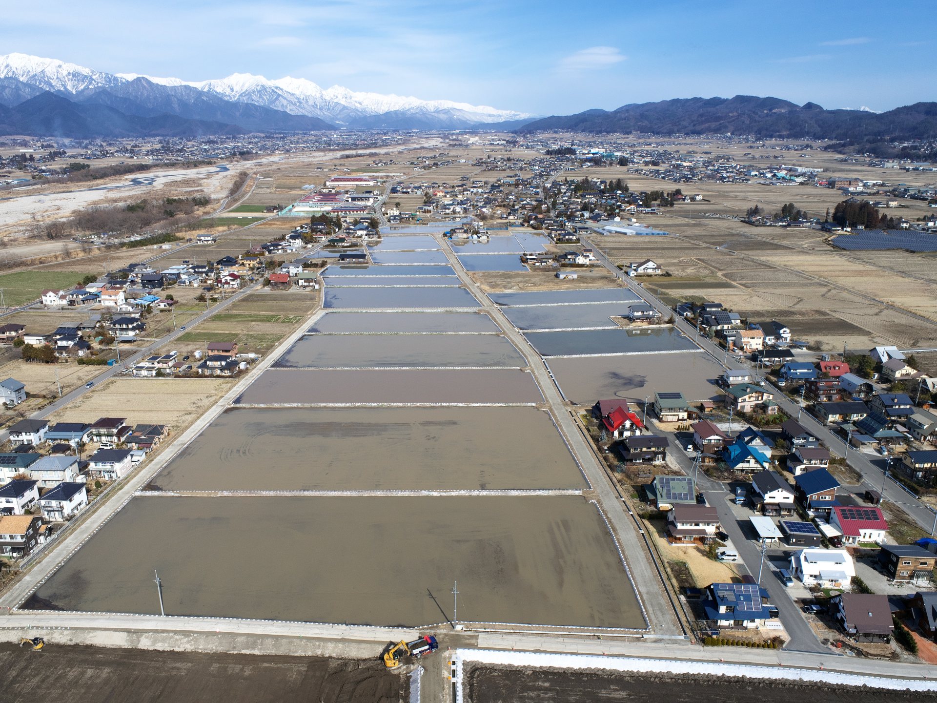 上空から撮影した会染西部地区、圃場整備第7工区。水の張られた新しい水田があり、奥には冬の晴れた北アルプスが見えている。